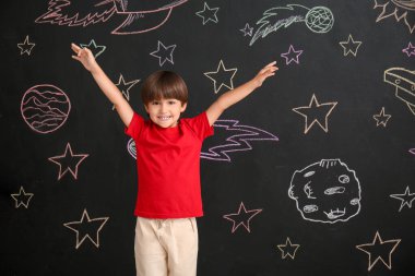 Siyah duvarın yanında küçük şirin bir çocuk.