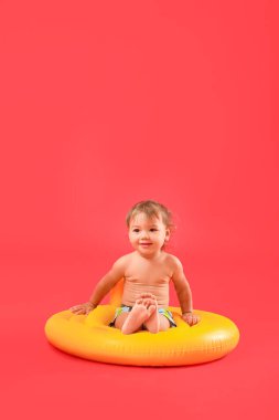 Renk arka planında şişirilebilir yüzüğü olan tatlı bir erkek bebek.