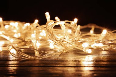 Koyu ahşap masada parlayan Noel ışıkları, yakın plan.