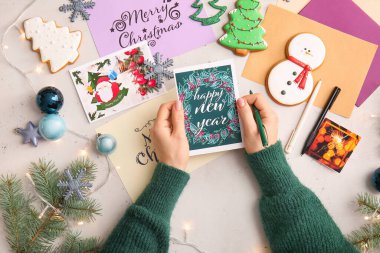 Noel ve yeni yıl kutlamaları için kartpostallar yazan bir kadın.