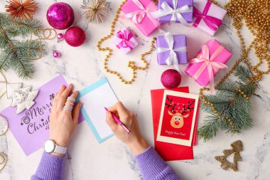Noel ve yeni yıl kutlamaları için kartpostallar yazan bir kadın.