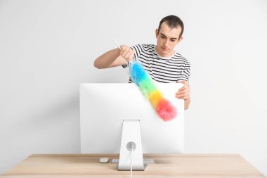 Işık arkaplanındaki bilgisayarı temizleyen adam