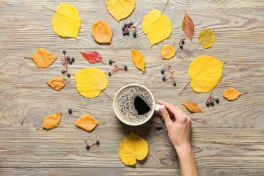 Bir fincan kahve ve ahşap arka planda sonbahar yapraklarıyla.