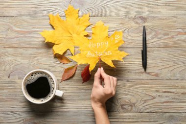 Sonbahar yaprakları ve ahşap arka planda bir fincan kahveyle.