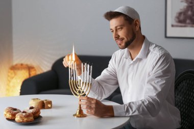 Man lighting candles for Hannukah at home clipart
