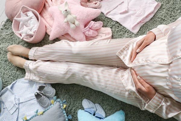 Güzel Hamile Bir Kadın Bebek Elbiseleriyle Yerde Oturuyor — Stok fotoğraf