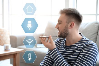 Odasında cep telefonu olan bir adam. Modern teknoloji ve akıllı ev otomasyonu