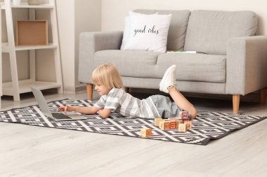 Evde dizüstü bilgisayarı olan şirin bir çocuk.