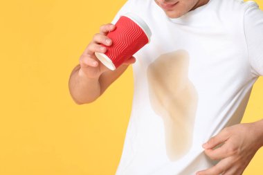 Tişörtünde kahve lekeleri olan stresli genç bir adam.