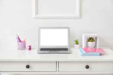 Beyaz duvarın yanında dizüstü bilgisayarı olan şık bir iş yeri