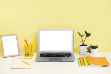 Renk duvarının yanında modern dizüstü bilgisayarı olan rahat bir iş yeri