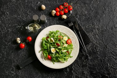 Lezzetli roka salatası ve koyu arkaplanda malzemeler.