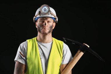 Karanlık arka planda baltası olan madenci.