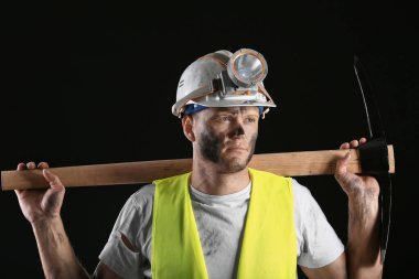 Karanlık arka planda baltası olan madenci.