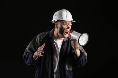 Karanlık arka planda megafonu olan madenci adam.