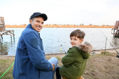 Küçük çocuk ve babası nehirde balık tutuyor.