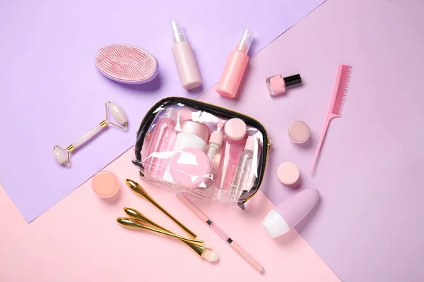 Travel cosmetics kit and transparent bag on color background