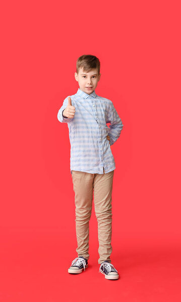 Cute boy showing thumb-up on color background