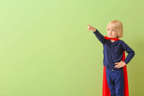 打扮成超级英雄的小男孩在彩色背景上展示着什么 — 图库照片