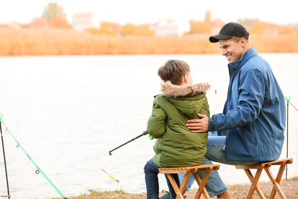 Little boy and his father fishing on river