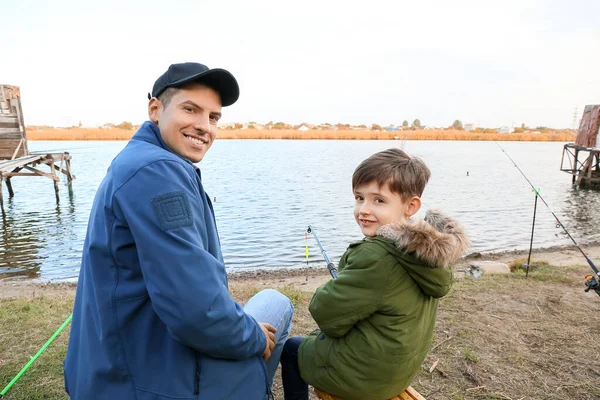 Küçük çocuk ve babası nehirde balık tutuyor.