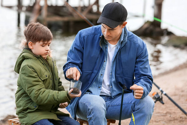 Little boy and his father fishing on river