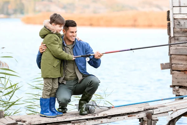 Little boy and his father fishing on river