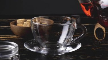 Masadaki cam fincana sıcak çay dökülüyor.