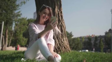 Güzel, genç bir kadın cep telefonunu dışarıyı aramak için kullanıyor.