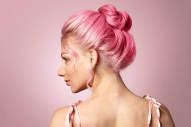Pembe arka planda olağandışı saçları olan güzel bir genç kadın.
