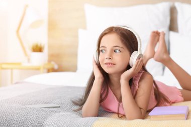 Yatak odasında müzik dinleyen tatlı küçük kız.