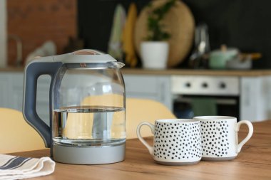 Masada bardakları olan elektrikli çaydanlık.