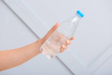 Kadın eli ve arka planda bir şişe su.