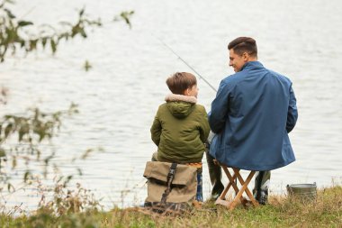 Küçük çocuk ve babası nehirde balık tutuyor.