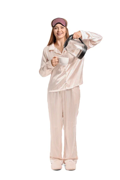 お湯を電気ケトルから白い背景にカップに注ぐパジャマの幸せな女性 — ストック写真