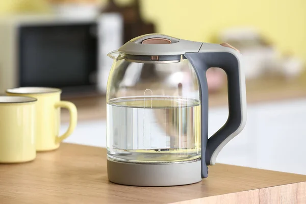 Electric kettle with cups on  table