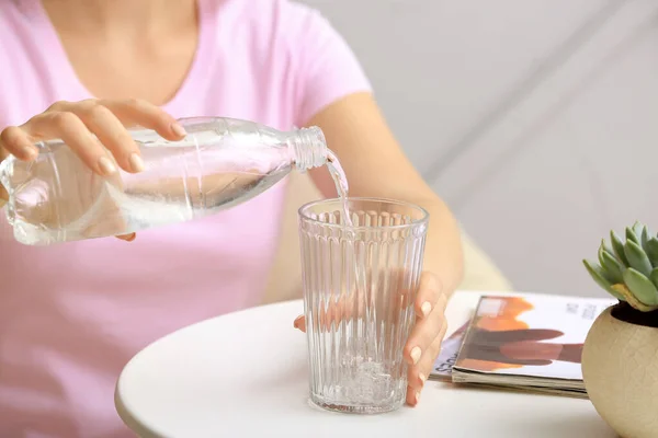 女人把水从瓶子倒到桌上的玻璃杯里 特写镜头 — 图库照片
