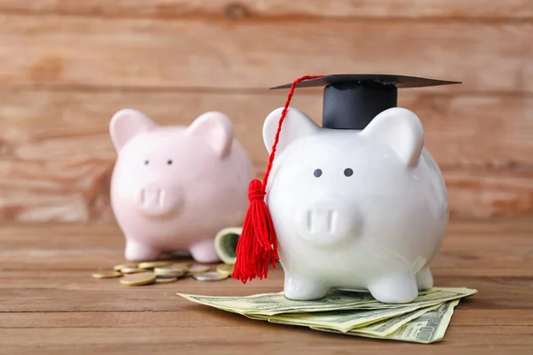 卒業帽子と木製の背景にお金を持つ貯金箱 授業料概念 — ストック写真
