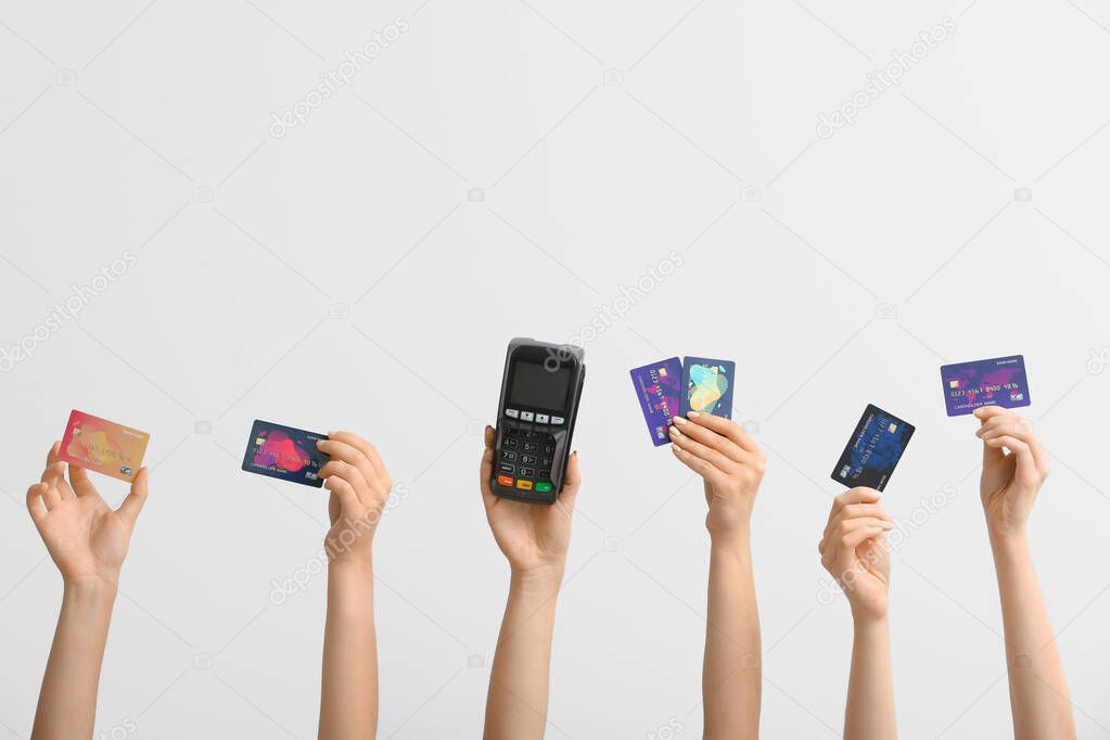 Female hands with credit cards and payment terminal on white background