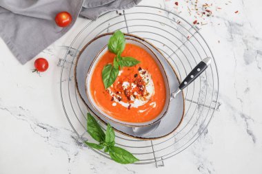 Arka planda bir kase lezzetli domates kremalı çorba.
