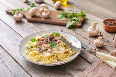 Tahta masada tavuk ve mantarlı bir tabak lezzetli makarna.