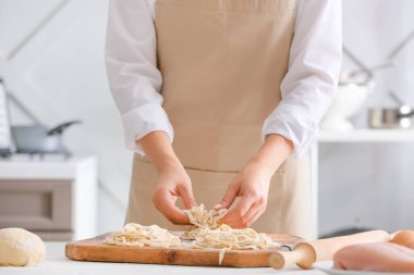 Kadın mutfakta çiğ makarna yapıyor.