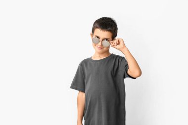 Beyaz arka planda şık güneş gözlüğü takan sevimli çocuk.