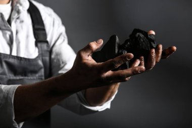 Koyu arkaplanda kömürü olan madenci, yakın plan.