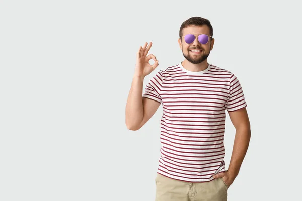 Schöner Mann Mit Stylischer Sonnenbrille Zeigt Geste Auf Hellem Hintergrund — Stockfoto