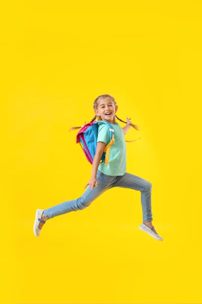 Saltando Pequeña Colegiala Sobre Fondo Color — Foto de Stock