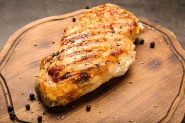 Koyu arkaplanda pişmiş tavuk filetosu olan tahta