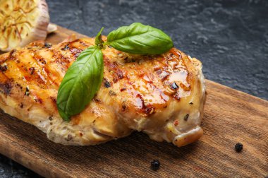 Koyu arkaplanda pişmiş tavuk filetosu olan tahta