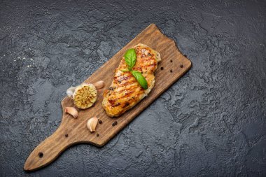 Koyu arkaplanda pişmiş tavuk filetosu olan tahta