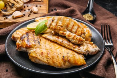 Koyu arkaplanda pişmiş tavuk fileto tabağı.